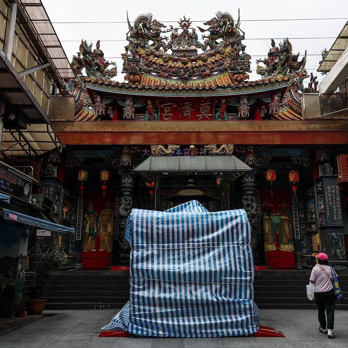 TOPSHOT - Statues outside Keelung's Dianji Temple are covered with protective tarpaulins ahead of the arrival of Typhoon Bavi in Keelung on July 10, 2026 (Photo by I-Hwa Cheng / AFP)