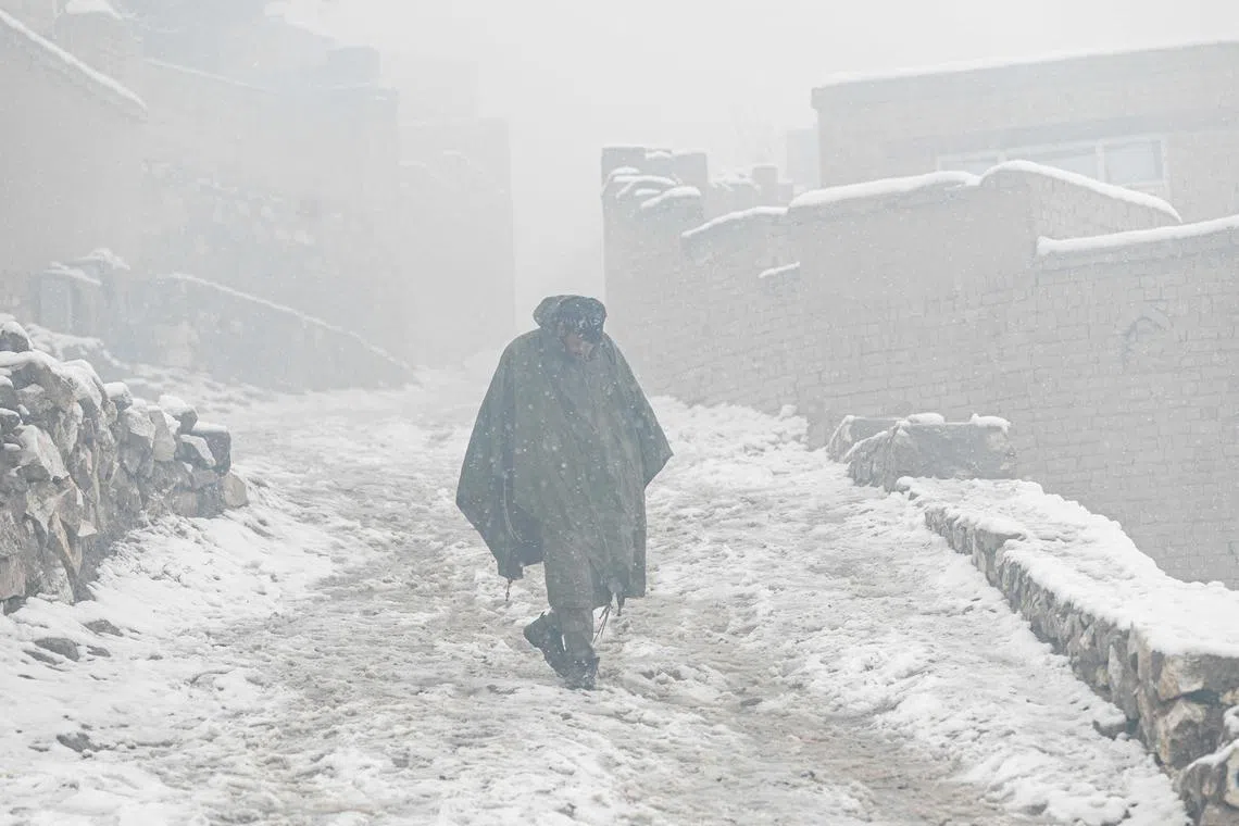 (FILES) In this file photo taken on January 8, 2023, an Afghan man walks down a street during snowfall in Kabul. - At least 166 people have perished in a wave of bitterly cold weather sweeping Afghanistan, officials said January 28, as extreme conditions continue to heap misery on the poverty-stricken nation. (Photo by Wakil KOHSAR / AFP)
