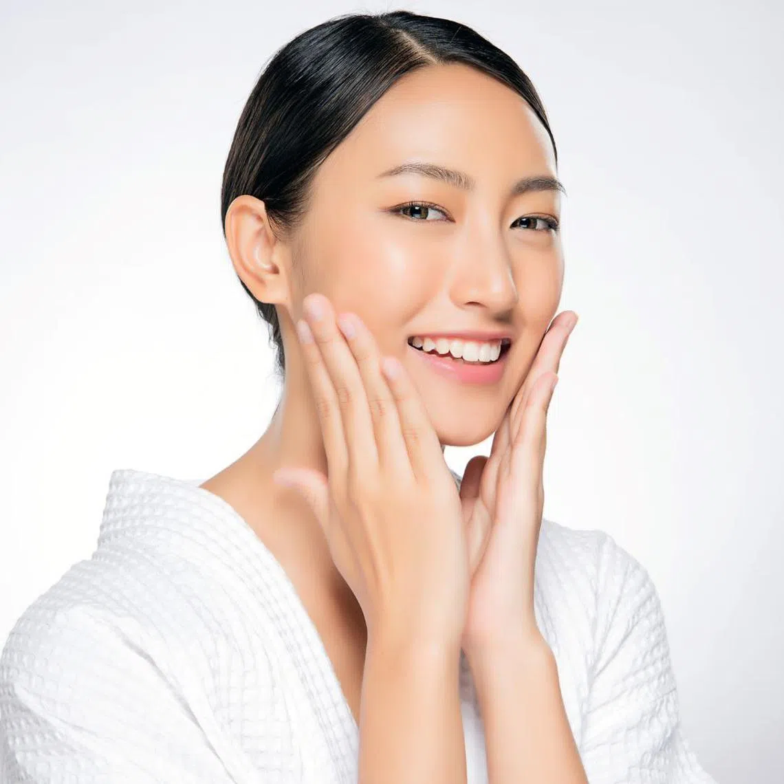 Pretty asian woman touching her face and looking happy