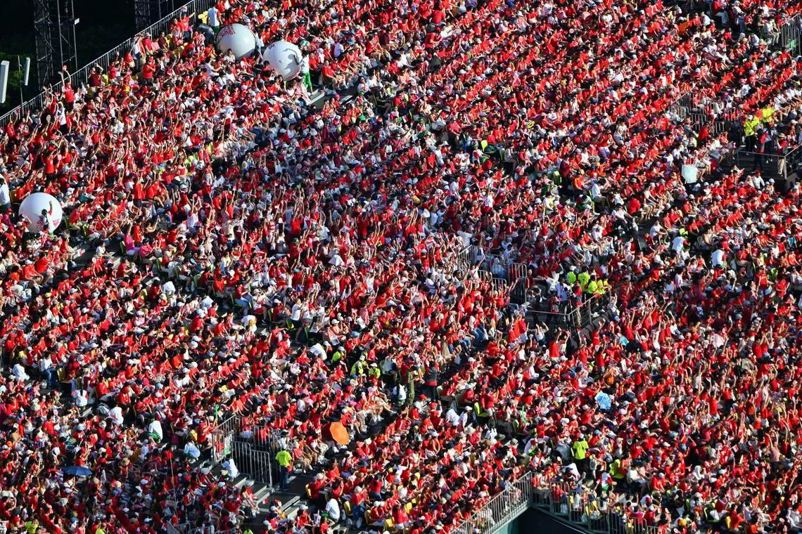 Spectators doing the wave at the National Day Parade at the Padang on Aug 9, 2023.