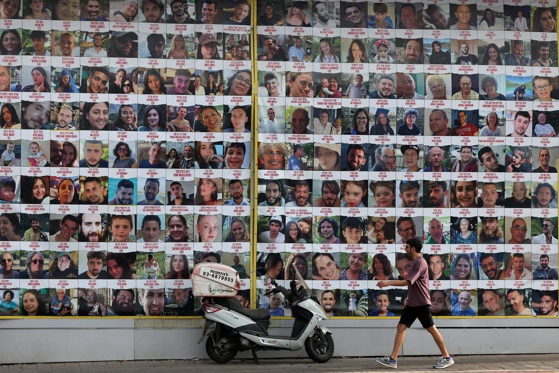 A man walks past a wall displaying posters of hostages in Tel Aviv, Israel. 