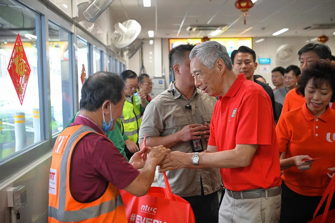 PM Lee Hsien Loong (right) distributing red packets to public transport workers at the Woodlands Integrated Transport Hub, on Jan 21, 2023.