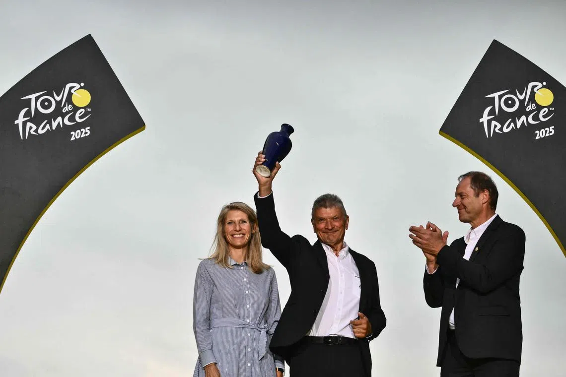 (From left) France's Minister for Sports, Youth, and Community Life Marie Barsacq watches as former French cyclist Bernard Thevenet recieves an award from general director of the Tour de France Christian Prudhomme on July 27.