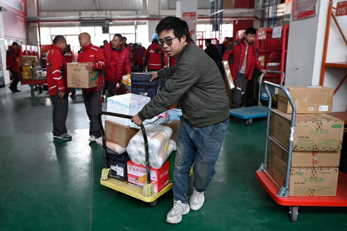 A worker pulls a trolley with packages for delivery after sorting at a JD.com warehouse in Beijing on November 11, 2024, known as the Singles’ Day shopping festival in China. (Photo by WANG Zhao / AFP)