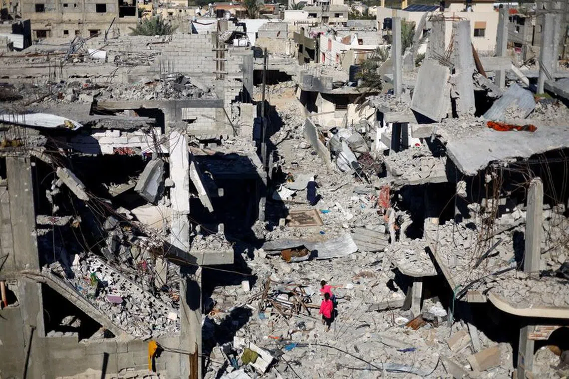 Palestinian children walk among the houses destroyed in Israeli strikes during the conflict, amid the temporary truce between Israel and the Palestinian Islamist group Hamas, at Khan Younis refugee camp, in the southern Gaza Strip, November 29, 2023. REUTERS/Mohammed Salem