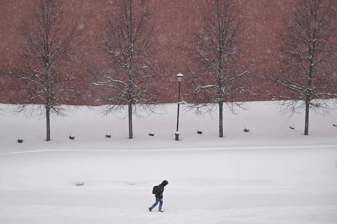 A person walking on the edge of Red Square outside the Kremlin during a heavy snowfall in Moscow on Feb 7, 2024.