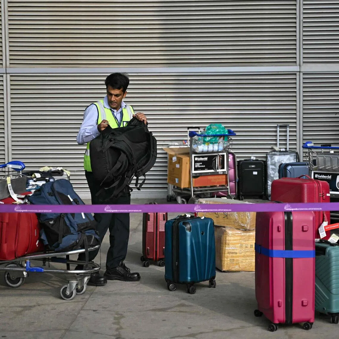 A ground staff member sorts luggage of stranded passengers at the baggage collection area of Kempegowda International Airport in Bengaluru on Dec 6.