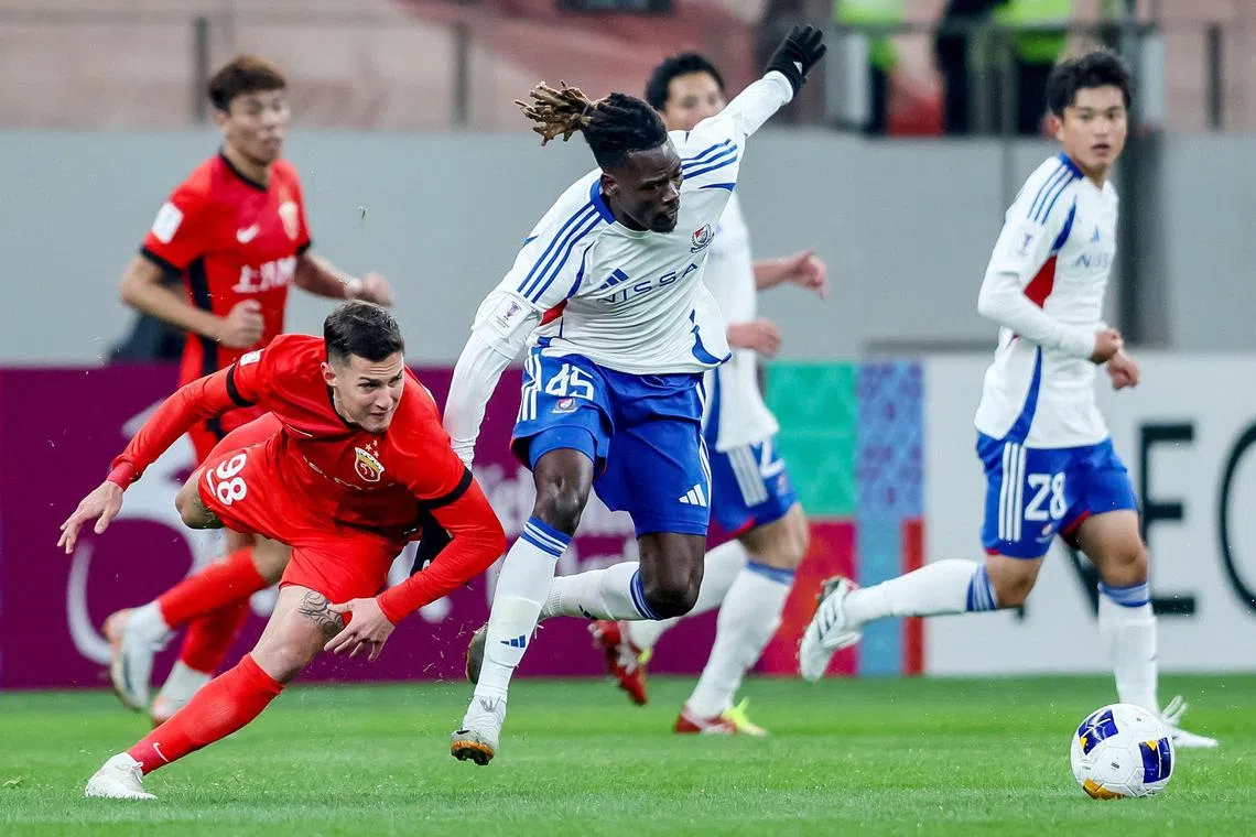 Yokohama F. Marinos' Kodjo Jean Aziangbe (centre) tussling for the ball with Shanghai Port's Mateus Vital during their AFC Champions League match in Shanghai on Feb 1.