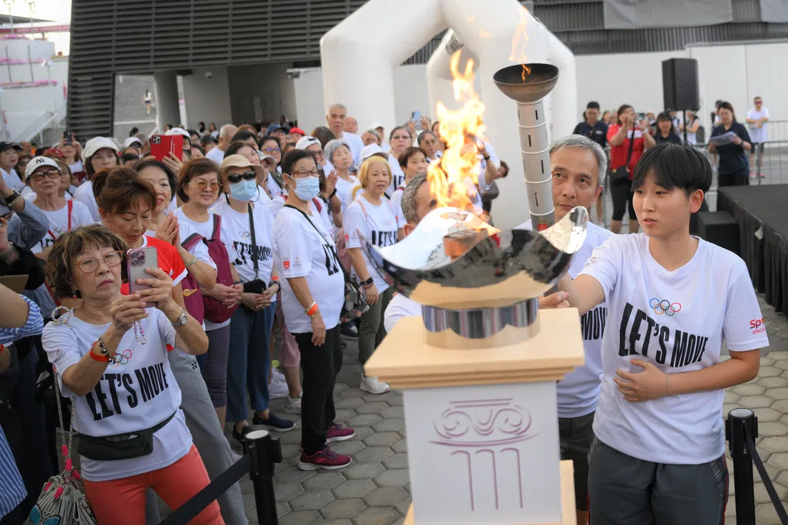 National paddler Zhou Jingyi (far right) and ex-Olympian Chua Koon Siong, light up the Olympic torch ahead of the Olympic Day Walk held at OCBC Square on Aug 29.