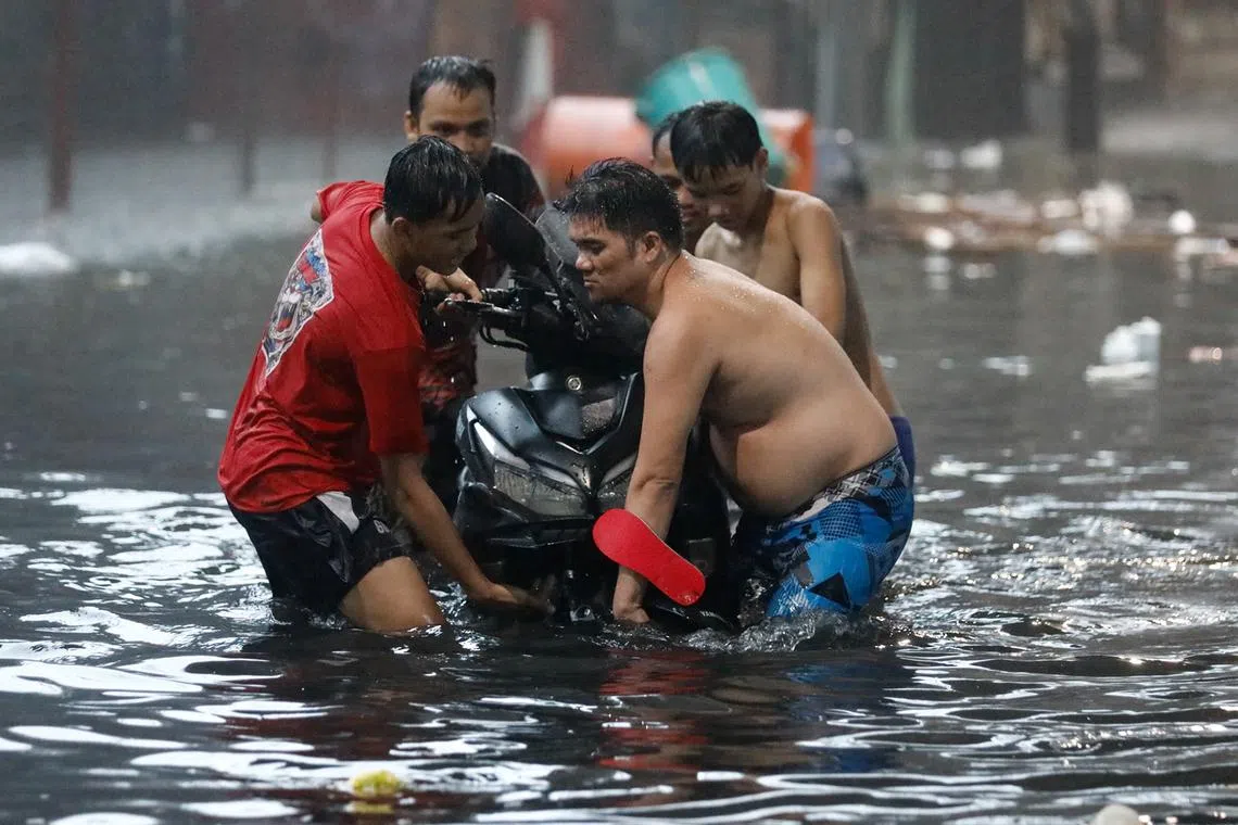 Residents carrying a motorcycle in flood water, following monsoon rainfall caused by Typhoon Gaemi, in Manila, on July 24, 2024. 