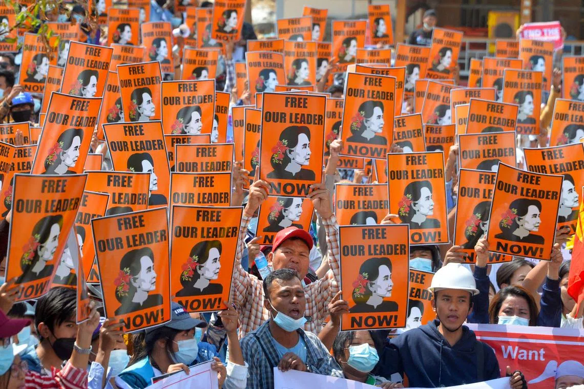 (FILES) In this file photo taken on February 28, 2021 protesters hold posters with the image of detained civilian leader Aung San Suu Kyi during a demonstration against the military coup in Naypyidaw. - A Myanmar junta court is expected to hear closing arguments for the last remaining charges against jailed democracy leader Aung San Suu Kyi on December 26, 2022, after the UN Security Council called for her release. (Photo by AFP)