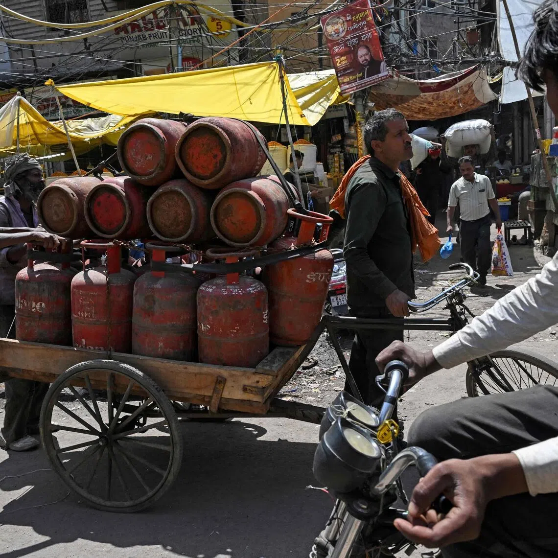 Workers transport liquefied petroleum gas (LPG) cylinders on a rickshaw for distribution at a spice market in the old quarters of Delhi on April 10, 2026.