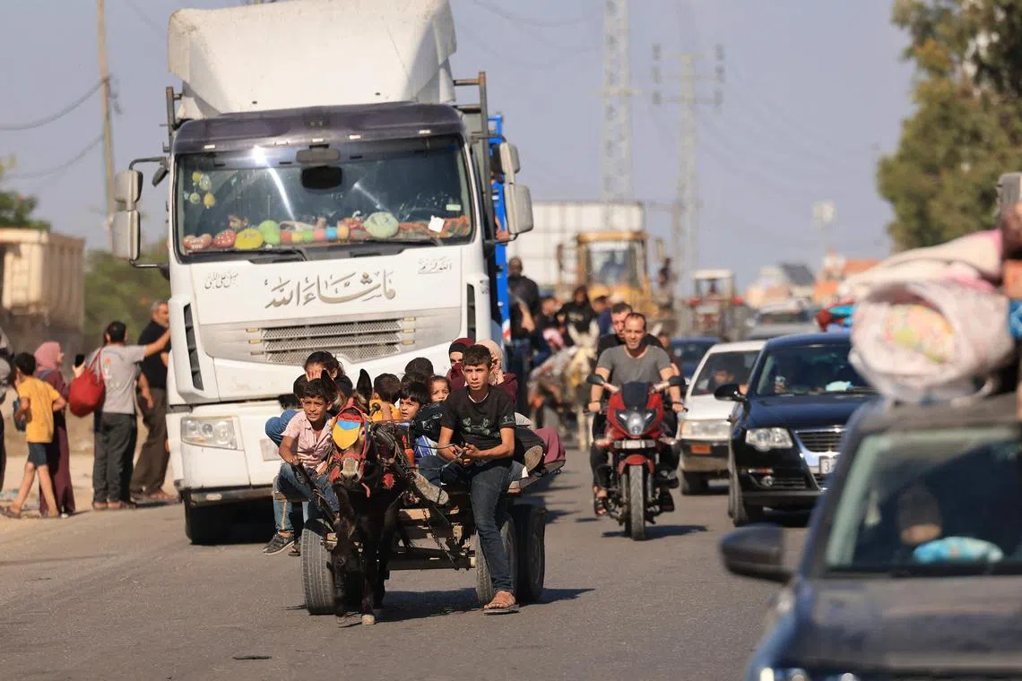 Palestinian carrying their belongings flee before an expected ground offensive, in Gaza City, on Oct 13, 2023.