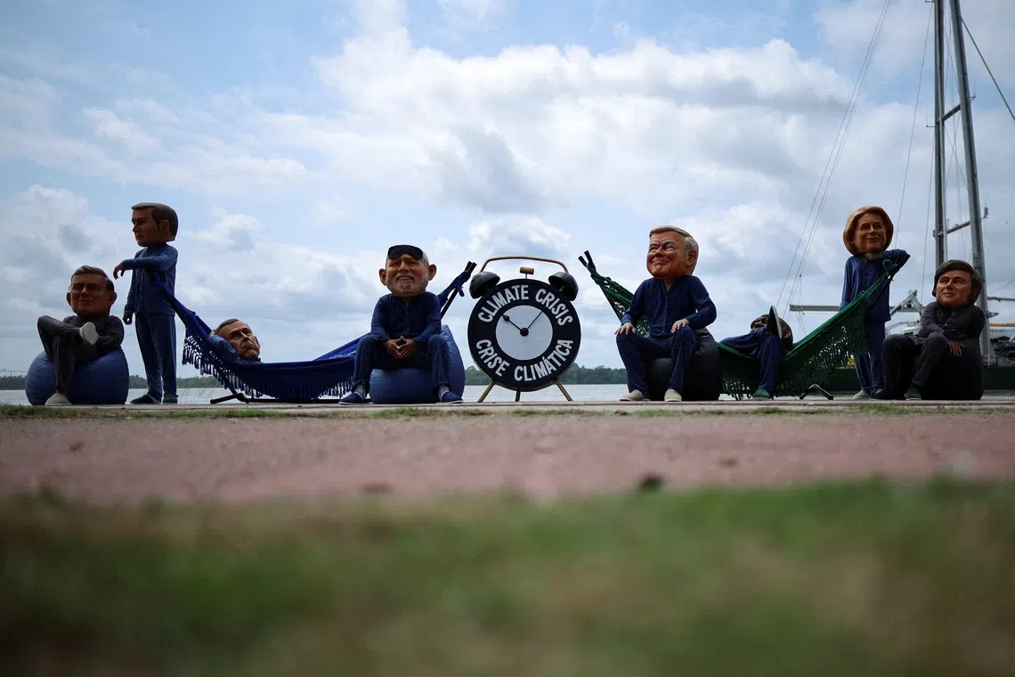 FILE PHOTO: Oxfam activists wearing big head masks depicting world leaders stage a \"Sleeping on the Job\" protest to criticize the inadequacy of decisions made by the world?s largest economies in combating the climate crisis, ahead of the United Nations Climate Change Conference COP30 in Belem, Brazil, November 5, 2025. REUTERS/Adriano Machado     TPX IMAGES OF THE DAY/File Photo