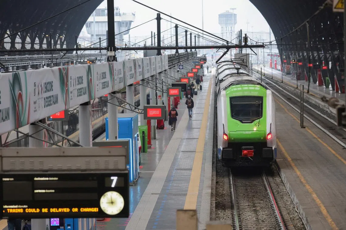 A regional train stands at the platform while passengers move along the concourse under strike-related service warnings at Milano Centrale station during a Trenord strike in Milan, Italy, February 2, 2026. REUTERS/Fabrizio Bensch