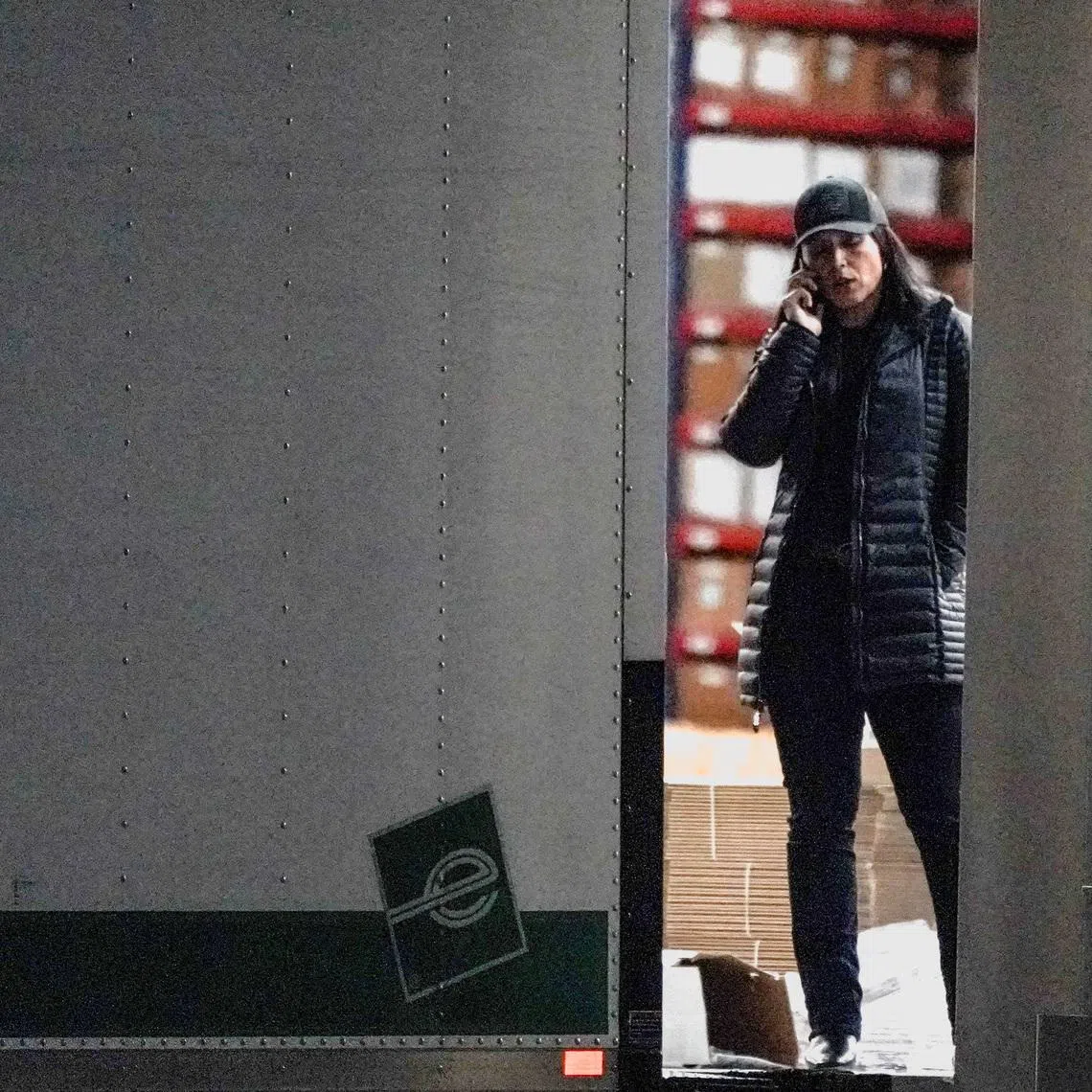 FILE PHOTO: U.S. Director of National Intelligence Tulsi Gabbard speaks on the phone while standing at the edge of a truck loading bay after the FBI executed a search warrant for the Fulton County Election Hub and Operation Center in relation to the 2020 election, according to a law enforcement official familiar with the matter, in Union City, Georgia, U.S. January 28, 2026.  REUTERS/Elijah Nouvelage./File Photo