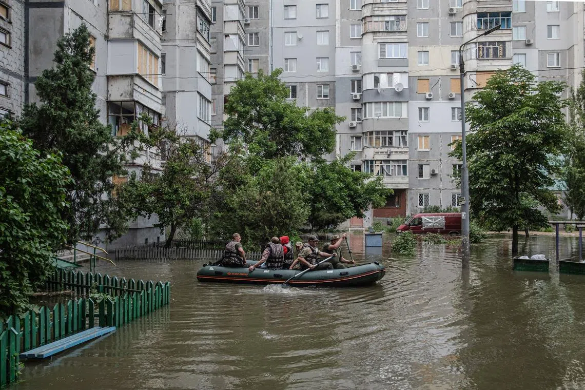 Residents using a rubber boat to evacuate from a flooded area of Kherson, Ukraine, on June 7, 2023. Ukraine has accused Russian forces of destroying a critical dam and hydroelectric power plant on the Dnipro River in the Kherson region on June 6. 