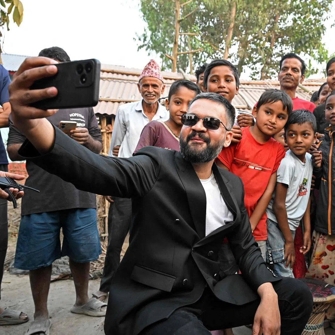 Nepal's PM-to-be Balendra Shah takes a selfie with children and supporters during a door-to-door election campaign at Gauriganj in Jhapa district on Feb 16, 2026.