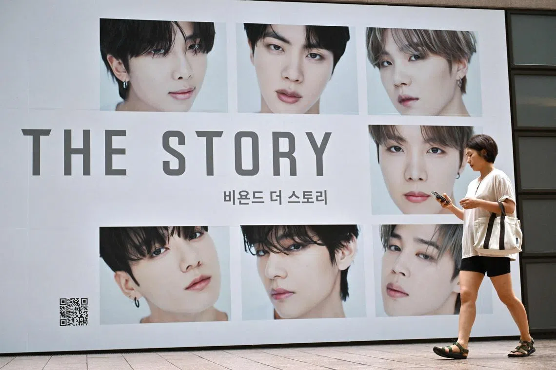 A woman walking past a poster for the BTS memoir in front of a bookstore in Seoul on July 9. BTS has played a significant role in promoting South Korea’s culture, once even serving as the country’s presidential envoys.