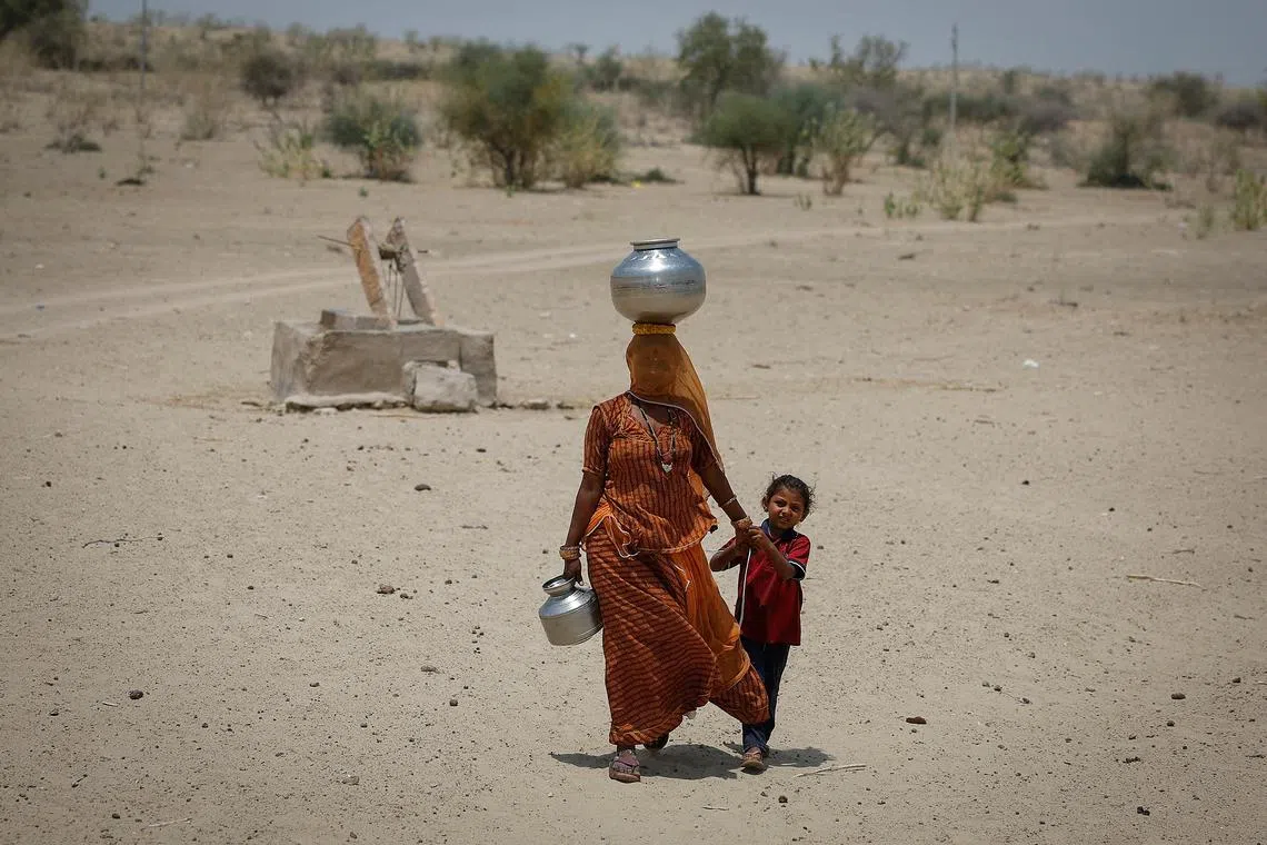 A woman walks back towards her home after filling water from a shallow well in a desert area on a hot summer day in Barmer, Rajasthan, India, April 26, 2024. REUTERS/Adnan Abidi/ File Photo