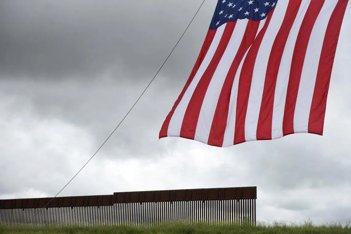 FILE PHOTO: A flag flies in front of a section of the border wall along the U.S.-Mexico border in Pharr, Texas, U.S. June 30, 2021.  REUTERS/Callaghan O'Hare/File Photo
