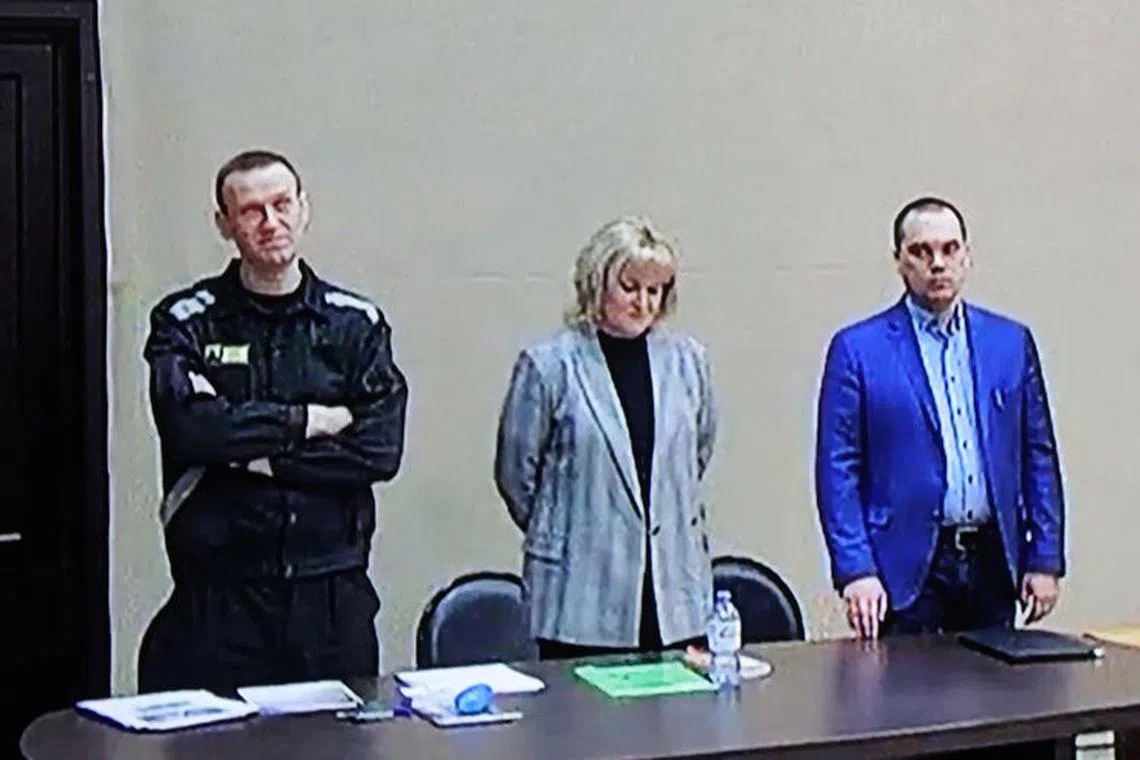 FILE PHOTO: Russian opposition leader Alexei Navalny, accused of fraud and contempt of court, his lawyers Olga Mikhailova and Vadim Kobzev are seen on a screen via a video link during a court hearing at the IK-2 corrective penal colony in the town of Pokrov in Vladimir Region, Russia March 22, 2022. REUTERS/Evgenia Novozhenina/File Photo