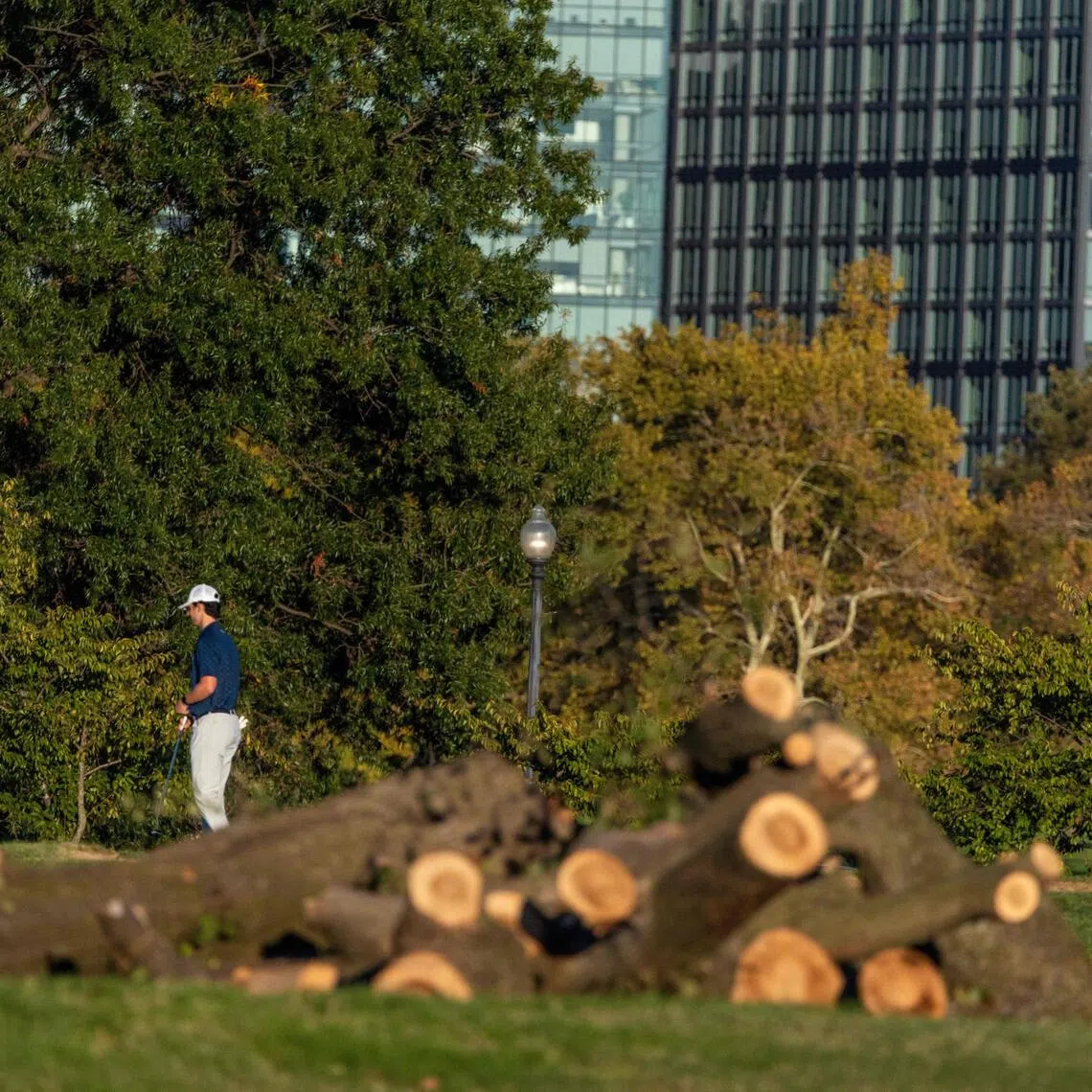 Golfers walk by piles of logs and debris on the course at East Potomac Golf Links on Oct 18.
