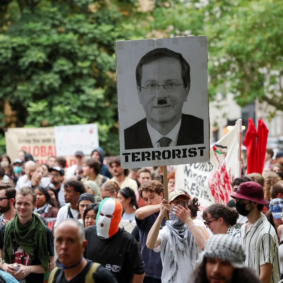 A demonstrator holds a sign with a picture depicting Israeli President Isaac Herzog during the 'Rally Against Police Brutality' following yesterday's clashes with police during a protest against Herzog's state visit to Australia, in Sydney, Australia, February 10, 2026. REUTERS/Hollie Adams