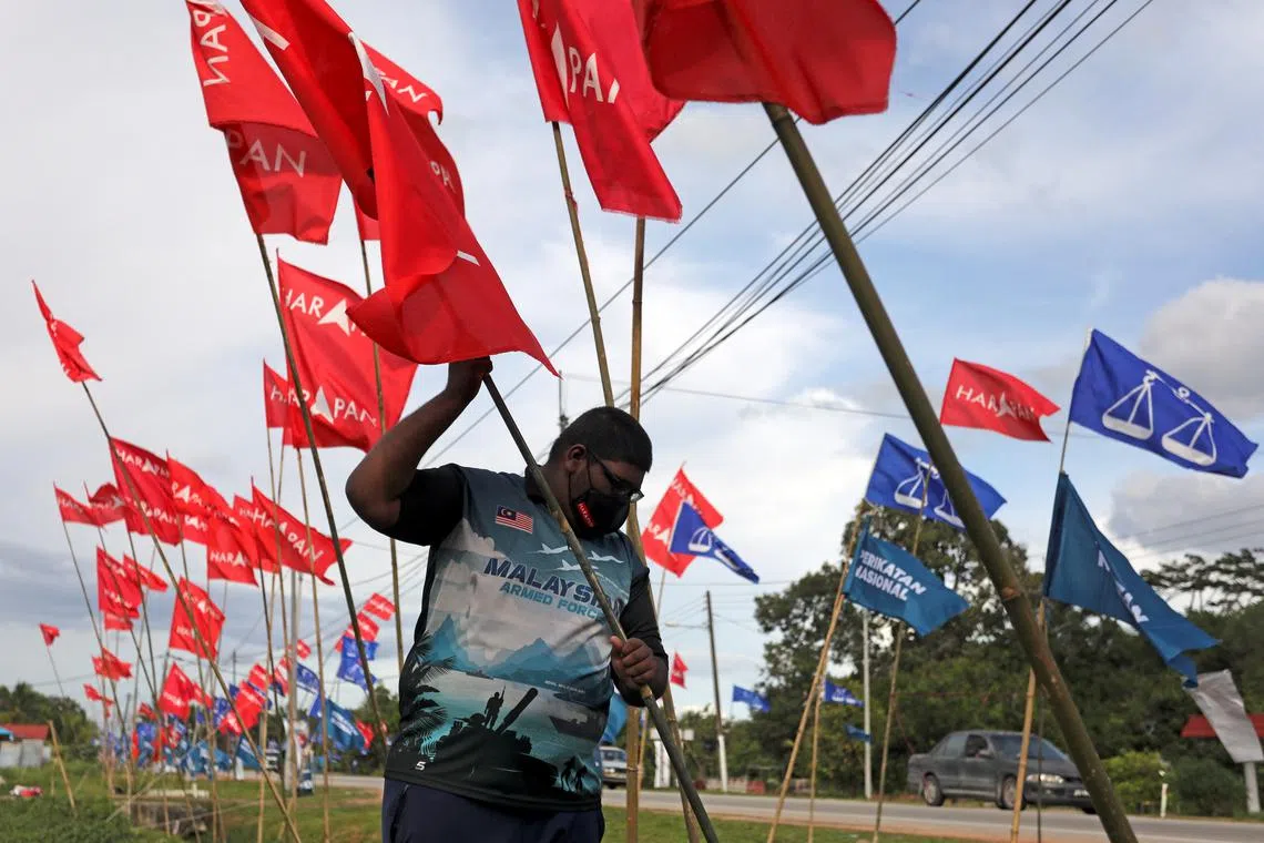 Muhd Faisal Abdullah puts up a Pakatan Harapan flag at Sungai Terap, Malaysia, on March 4, 2022. 