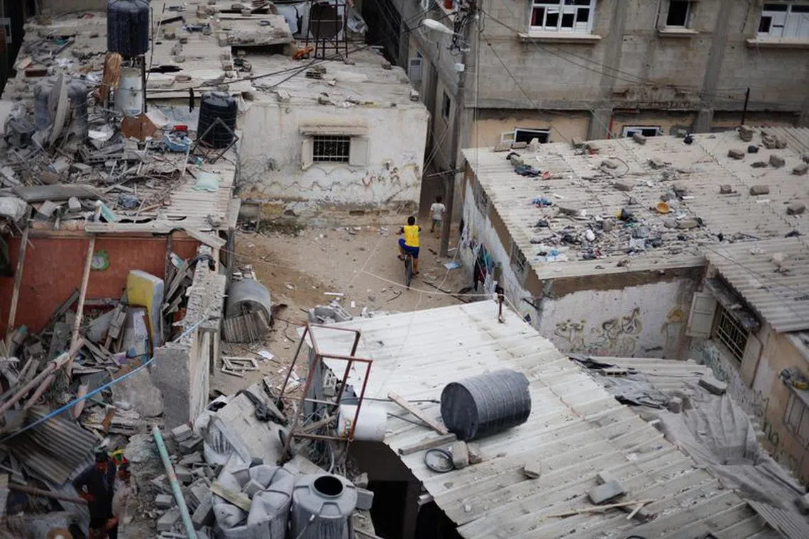 A Palestinian boy rides a bike, as Emergency personnel and people check the damage at the site of Israeli strikes on houses, amid the ongoing conflict between Israel and Palestinian Islamist group Hamas, in Khan Younis in the southern Gaza Strip, October 29, 2023. REUTERS/Mohammed Salem