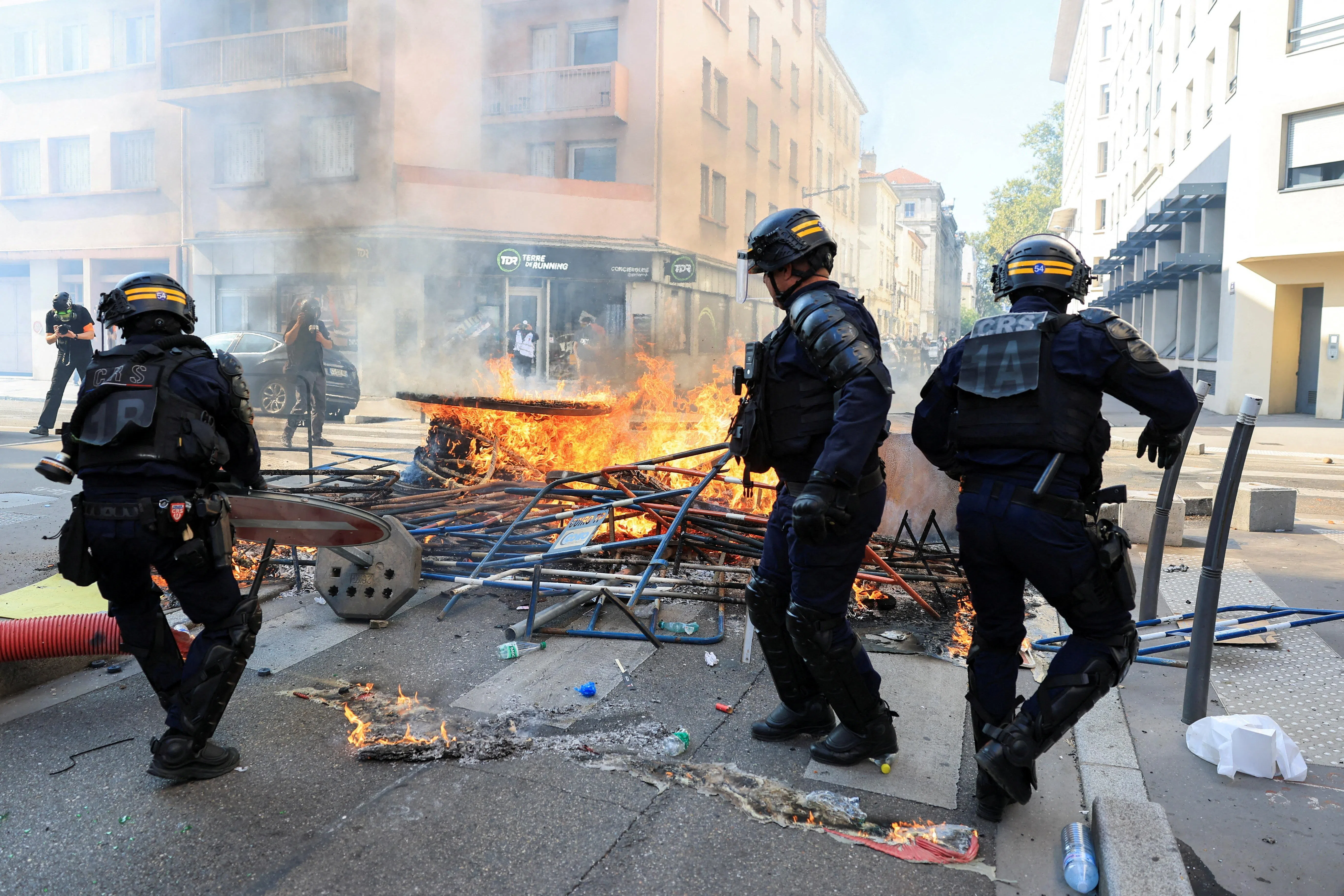 French riot police removing elements of a burning street barricade in the French city of Lyon on Oct 6.