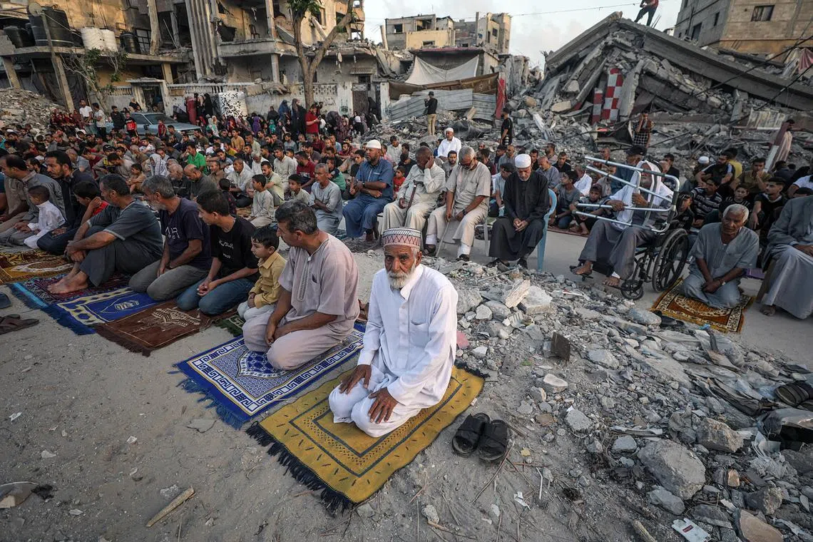 Palestinians gather for the Eid al-Adha prayer in Khan Younis city in southern Gaza, their frayed prayer mats next to mounds of rubble.