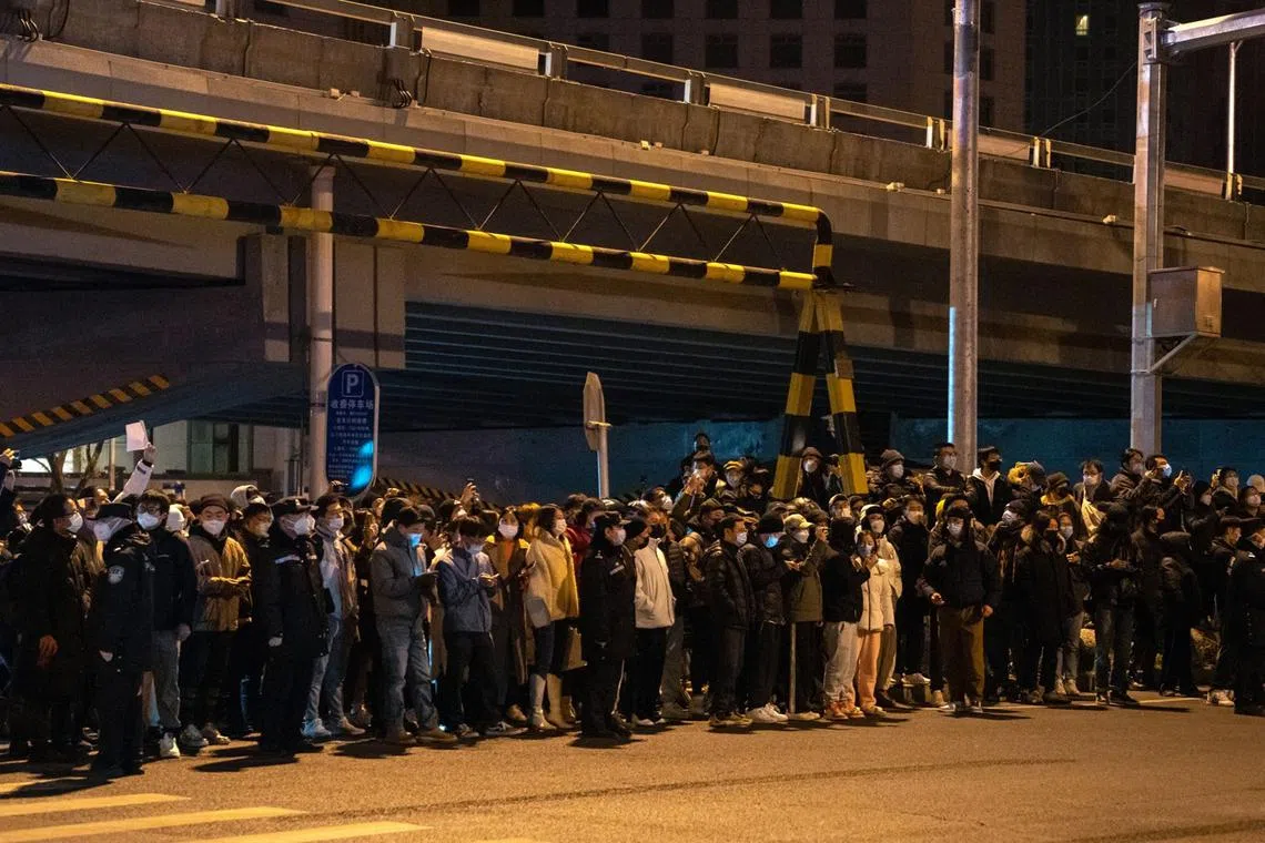 Onlookers stand by the road during a protest in Beijing, China, Nov 28, 2022. 