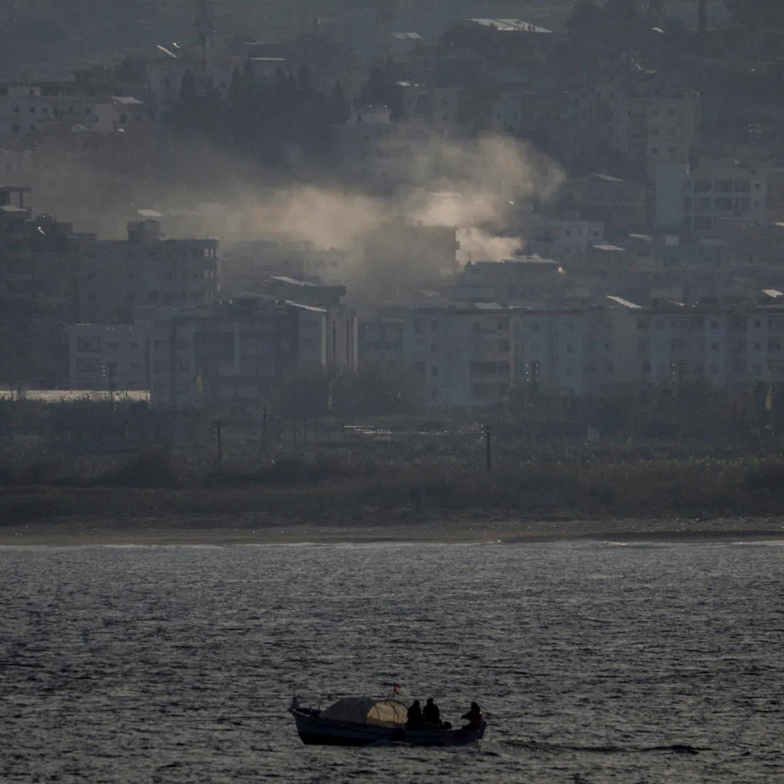 FILE PHOTO: Fishermen sail their boat as smoke from an Israeli airstrike rises in Abbassiye area in Tyre, Lebanon, April 14, 2026. REUTERS/Louisa Gouliamaki/File Photo