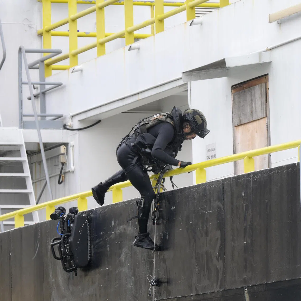 Members of the Police Coast Guard Special Task Squadron climb a caving ladder deployed by a hull climbing robot (left) on Jan 22, 2025. 