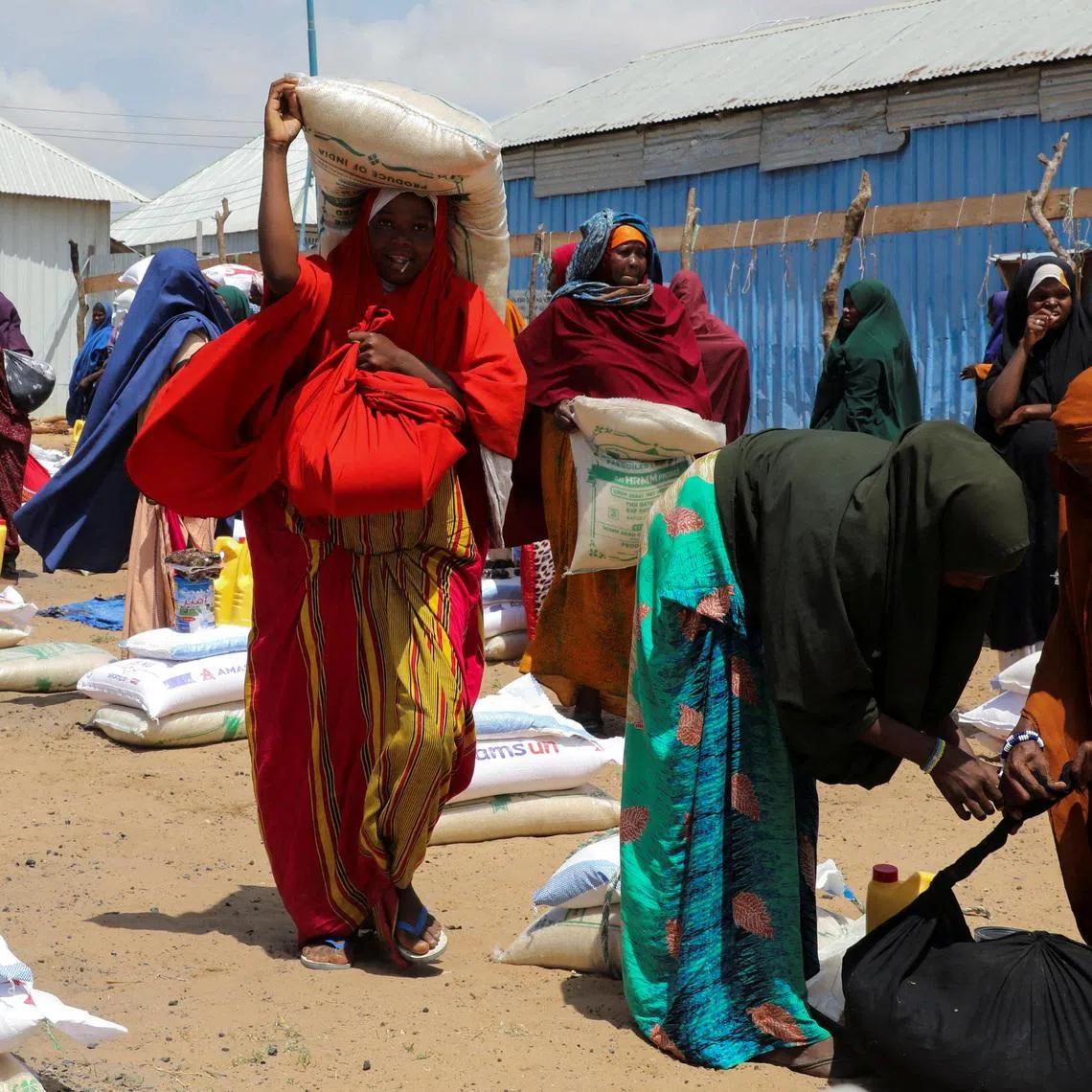 FILE PHOTO: Internally displaced Somali women carry their relief packages after receiving dry relief food from Kuwait charity, during the Muslim holy fasting month of Ramadan, in Mogadishu, Somalia March 12, 2025. REUTERS/Feisal Omar/File Photo