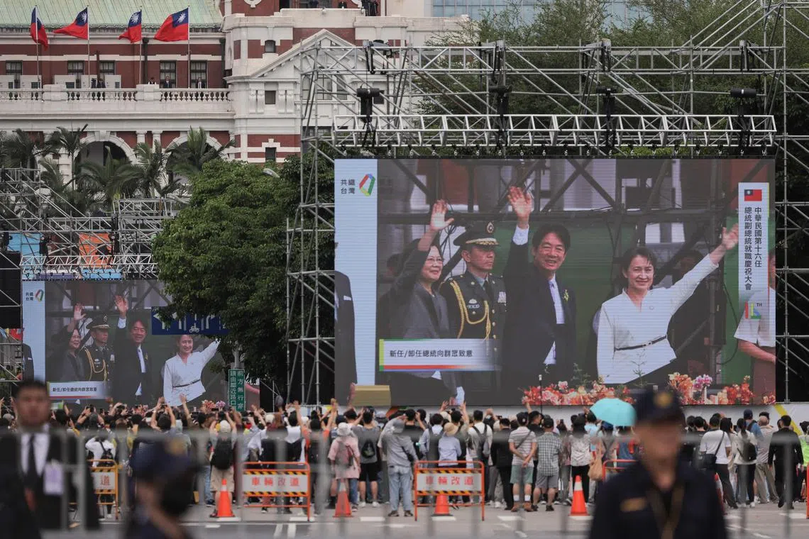 People watching a screen showing as Taiwan's President Lai Ching-te (C) and Vice President Hsiao Bi-khim (R) wave alongside outgoing president Tsai Ing-wen (L) during the inauguration ceremony at the Presidential Office Building in Taipei on May 20, 2024. 