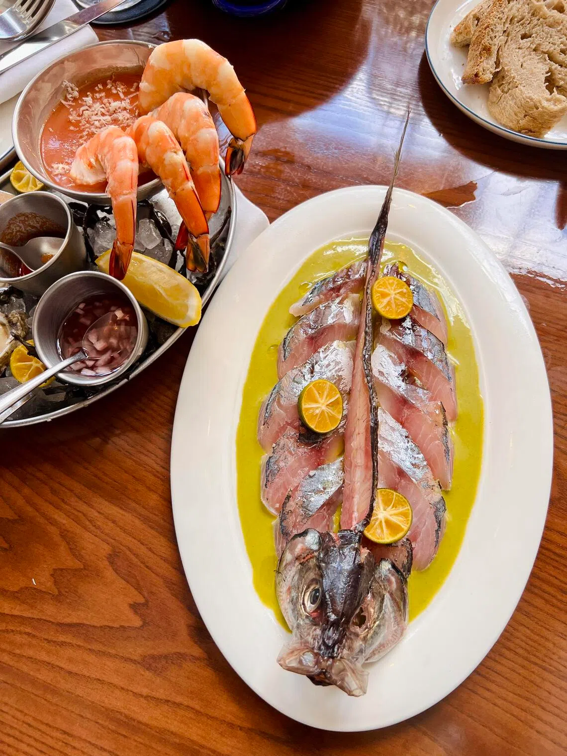 Whole deconstructed horse mackerel sashimi paired with a tangy Peruvian aji amarillo sauce, alongside a chilled seafood platter at Scuba BKK.