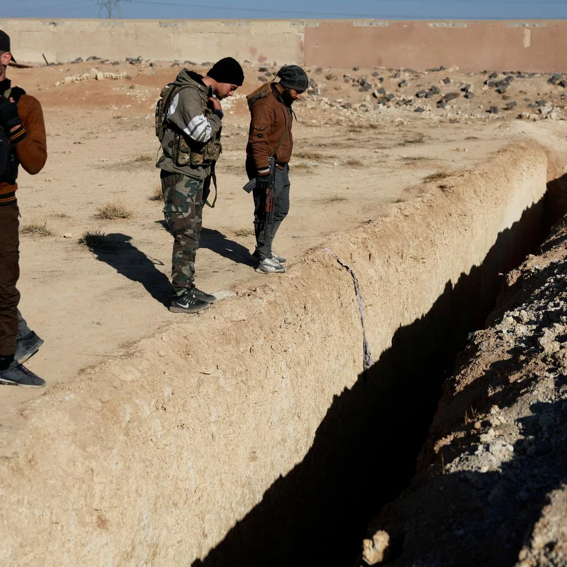 Fighters of the ruling Syrian body inspect the site of a mass grave from the rule of Syria's Bashar al-Assad, according to residents, after the ousting of al-Assad, in Najha, Syria, December 17, 2024. REUTERS/Ammar Awad