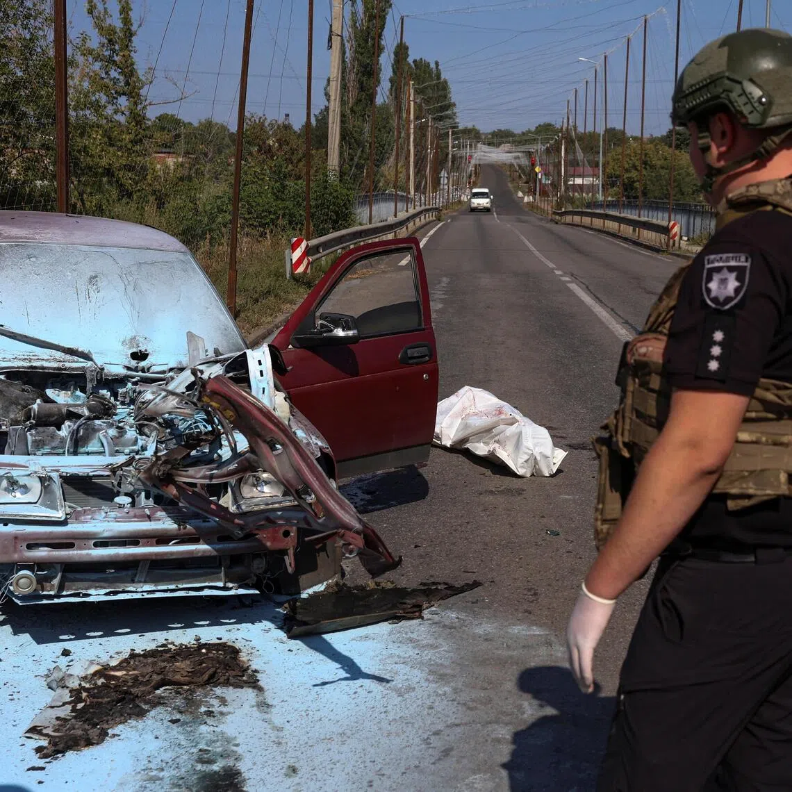 A police officer standing near the body of a resident who was killed in his car by a Russian drone strike, in the front-line city of Kramatorsk, Ukraine, on Sept 12.