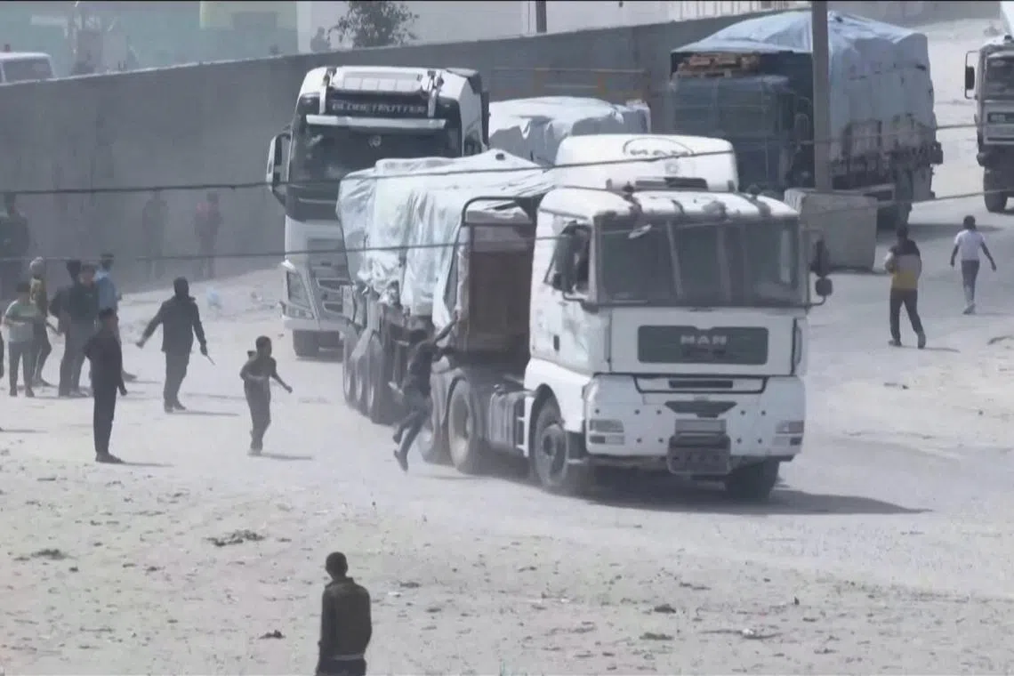 People chase a convoy of aid trucks driving into Gaza from Rafah crossing on April 9.