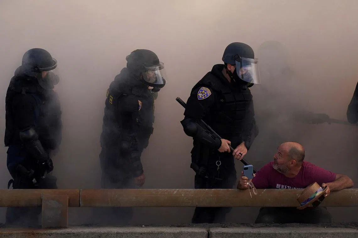 Police officers looking at a demonstrator during a protest against federal immigration sweeps in downtown Los Angeles, California, US, June 8, 2025. 