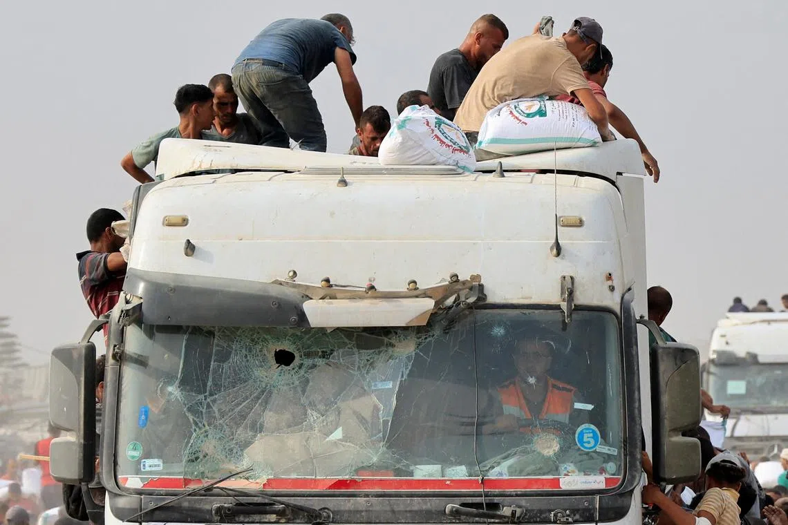 Palestinians scrambling to take aid from trucks that entered the southern Gaza Strip on Aug 12.