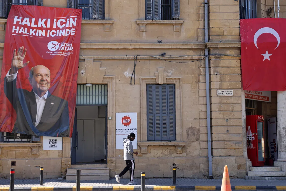 A person walks past a campaign poster of Turkish Cypriot leader and candidate Ersin Tatar ahead of the Turkish Cypriot presidential election in the Turkish-controlled northern Cyprus, in the divided city of Nicosia, Cyprus, October 18, 2025. REUTERS/Yiannis Kourtoglou