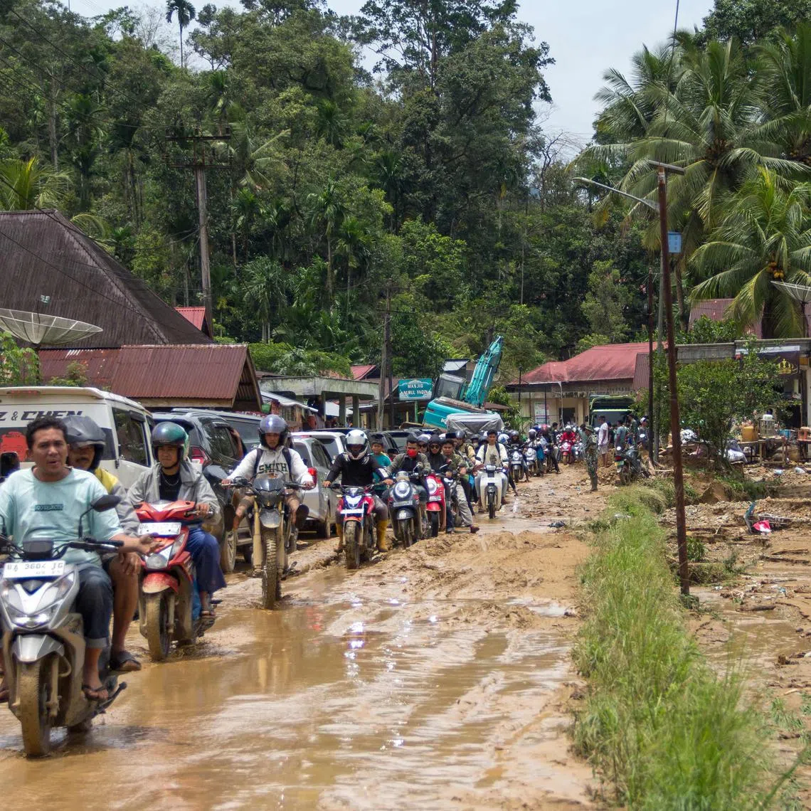 Motorists drive through a muddy road following flash flooding in Pesisir Selatan Regency, West Sumatra on March 9, 2024, after days of heavy rain across the province. At least 10 people were killed and 10 others were missing after flash floods and a landslide on the Indonesian island of Sumatra, a local official said on March 9. (Photo by REZAN SOLEH / AFP)