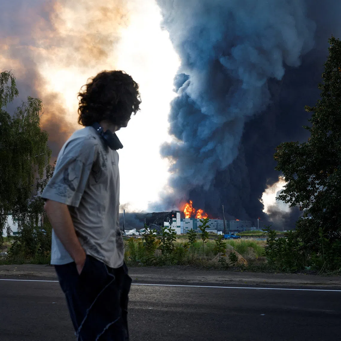 FILE PHOTO: A man looks on as smoke rises over a warehouse, which was hit by a Russian drone strike, amid Russia's attack on Ukraine, in Kyiv region, Ukraine, August 27, 2026. REUTERS/Valentyn Ogirenko/File Photo