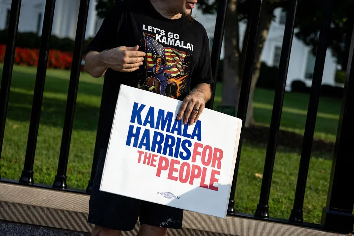 A man wearing a 'Let’s Go Kamala' shirt holds a sign supporting US Vice President Kamala Harris along Pennsylvania Avenue in front of the White House in Washington, DC, on July 21, 2024. Joe Biden has dropped out of the US presidential election and endorsed Vice President Kamala Harris as the Democratic Party's new nominee.