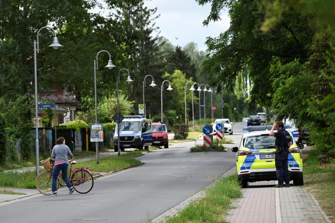 A woman with a bike speaks to a police man in a residential area after Berlin police warned the public that a suspected lioness was on the loose, in Stahnsdorf, near Berlin, Germany July 20, 2023. REUTERS/Annegret Hilse


