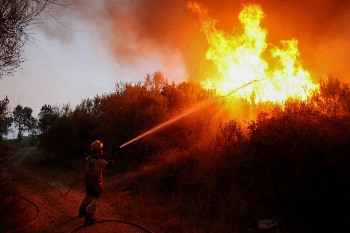FILE PHOTO: A firefighter uses a hose as smoke and flames from a wildfire rise in Vilar de Condes, in the province of Ourense in Galicia, Spain, August 15, 2025. REUTERS/Nacho Doce/File Photo