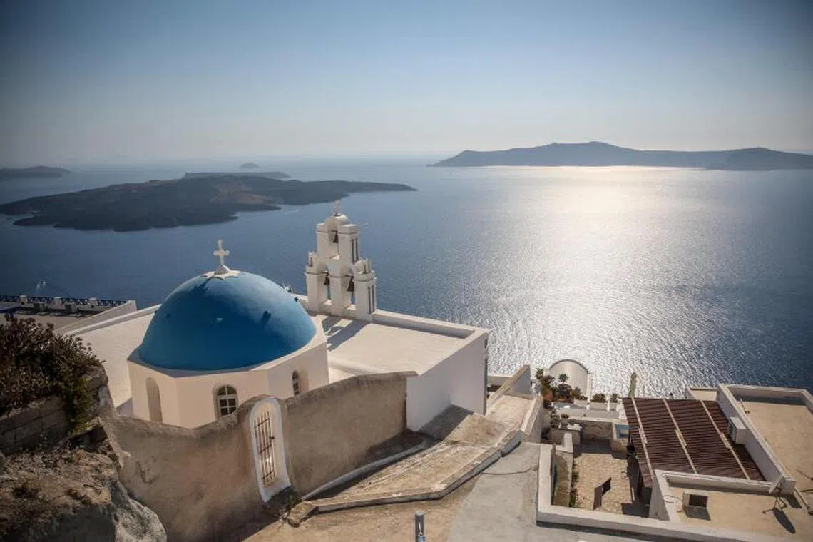 (FILES) This general view shows the Three Bells of Fira, the Catholic Church of the Dormition, in the village of Fira on the Greek island of Santorini on July 19, 2024. Schools on the Greek tourist island of Santorini will remain closed on February 3, 2025, after dozens of small earthquakes shook the region, civil protection authorities announced. Government officials, including Civil Protection Minister Vasilis Kikilias ordered the move on February 2, after a series of tremors in the sea around Santorini and surrounding islands, the site of one of the largest volcanic eruptions in recorded history. (Photo by Aris Oikonomou / AFP)